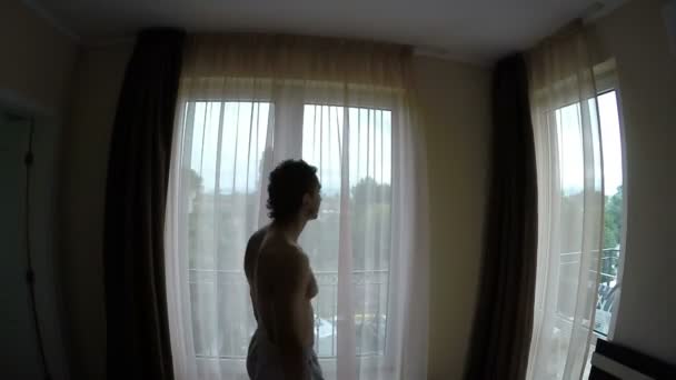 Человек закрывает шторы по утрам — стоковое видео