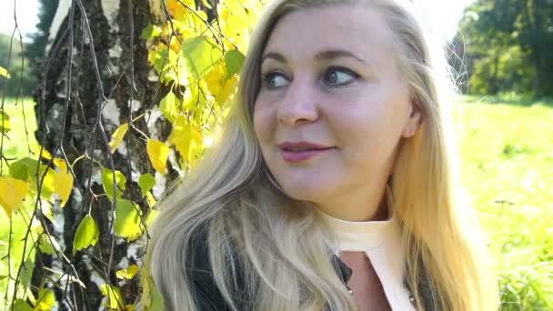 Zamyślony piękne Blondynka w parku siedzi i myśli o pleasunt liści jesienią żółte tło — Wideo stockowe