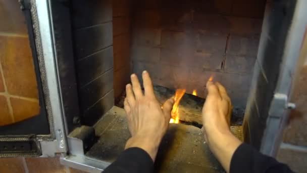Чоловік розслабляється теплим вогнем і розігріває руки, приємний зручний камін в будинку за містом — стокове відео