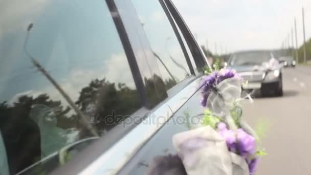 Ramo de boda de flores violetas púrpura soplando en el viento en coche de montar, feliz pareja recién casada — Vídeos de Stock
