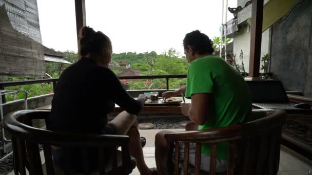 Pareja feliz desayunar en la terraza en la hermosa isla bali indonesia, fondo maravilloso, familia sentada en un balcón, vacaciones, vacaciones — Vídeo de stock