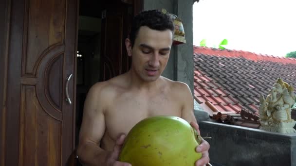 Красивый мужчина, пьющий кокос на террасе, замедленная съемка, азиатский бали — стоковое видео