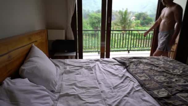Jeune homme heureux tombant sur le lit dans la chambre d'hôtel, se détendre sur son concept de vacances — Video
