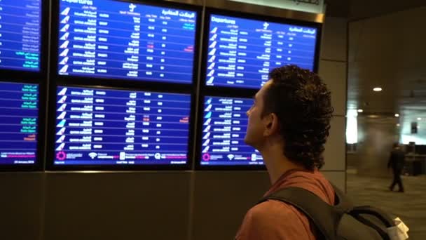 Passeggero uomo guardando schermo bordo orario presso il terminal dell'aeroporto, volo internazionale, uomo d'affari viaggia all'estero concetto — Video Stock