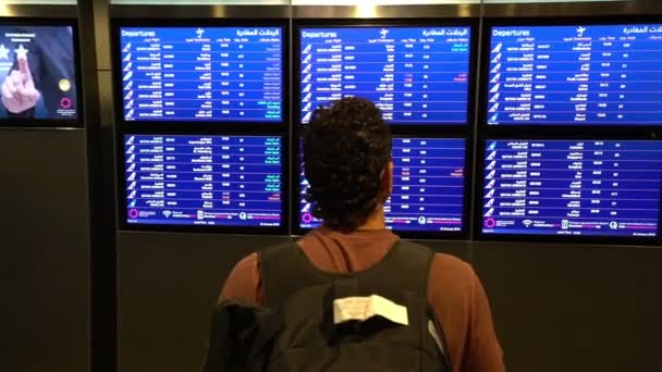 Man passenger looking at timetable board screen at the airport terminal, international flight, business man travels abroad concept — Stock Video