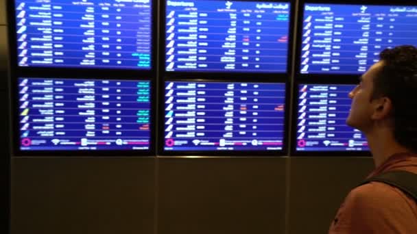 Человек пассажир смотрит на экран расписания на терминале аэропорта, международный рейс, деловой человек путешествует за границу концепции — стоковое видео