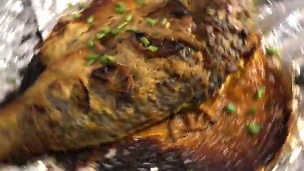 Carp has been roasted on the open fire with tomatoes and vegetables and lies on the board with sauce ready for eating, grilled fish, grill and barbecue, cooking outside, summer meals, countryside food — Stock Video