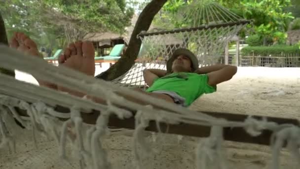 Fauler müder Mann entspannt sich in der Hängematte an einem schönen Tag am Strand, Reisekonzept — Stockvideo