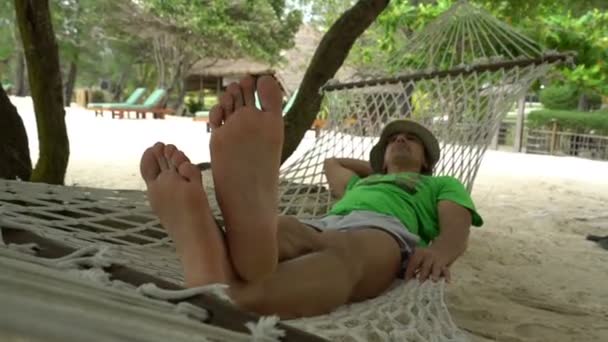 Paresseux fatigué homme relaxant sur l'hamac dans une belle journée sur la plage, voyage vacances concept — Video