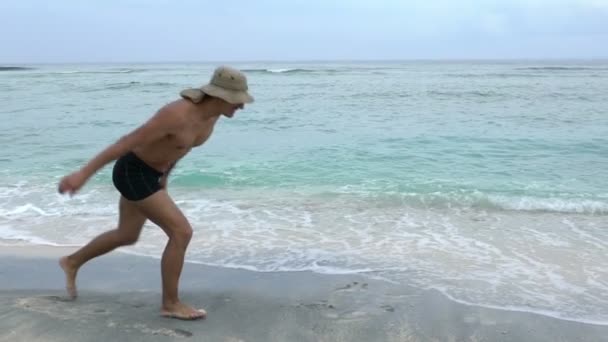 Jeune sportif ajustement bel homme sautant de joie sur la plage faisant roue et un peu de plaisir, vacances d'été concept — Video