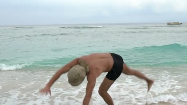Joven deportivo ajuste guapo hombre saltando de alegría en la playa haciendo rueda y un poco de diversión, vacaciones de verano concepto — Vídeos de Stock