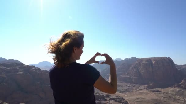 Mujer viajera de pie al borde de las montañas y mostrando señal de amor — Vídeos de Stock