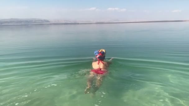 Rolig kvinna försöker simma i ett dött hav, floationg ass, naturlig jordanien, klumpiga turister — Stockvideo