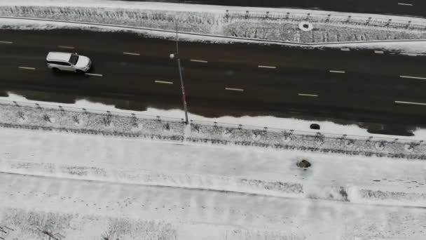 Coche blanco que conduce por el camino vacío de la nieve del invierno, tiro aéreo — Vídeos de Stock