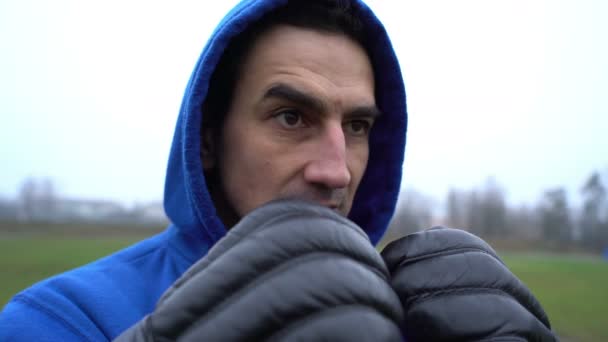 Bokser mężczyzna w rękawiczkach bokserskich, problem z gniewem, mężczyzna w kapturze wygląda agresywnie, próbuje sprowokować — Wideo stockowe