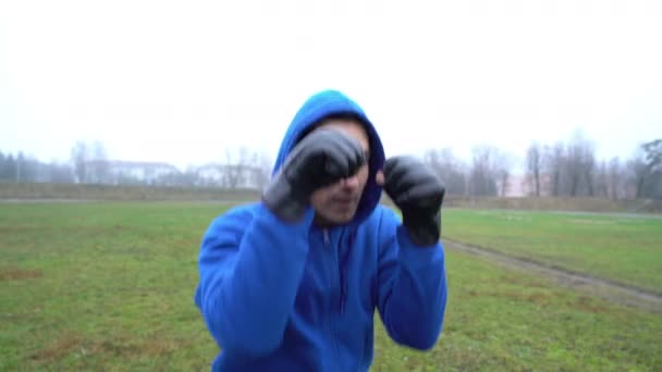 Hombre deportista boxeador chico usando guantes de boxeo entrenamiento al aire libre, haciendo sentadillas y golpes en, hombre en — Vídeo de stock