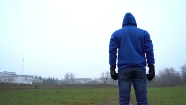 Koncepcja samotności, człowiek sam stojący na zewnątrz w parku, widok z tyłu, noszenie rękawic bokserskich, walka — Wideo stockowe