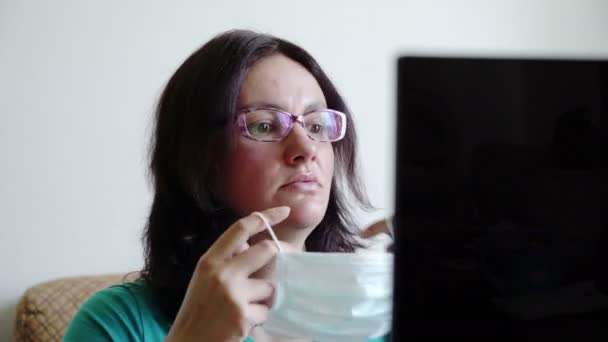 女性はマスクをつけてノートパソコンでウィルスの流行を読み取りショックを受け — ストック動画