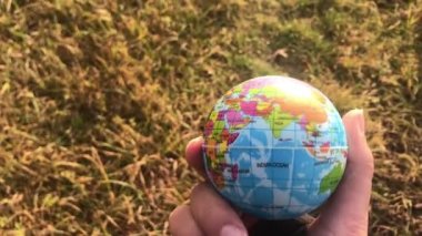 Küresel toprağı elinde tutan kadın, sarı çimenlere, ekoloji konseptine, insan etkisine karşı,