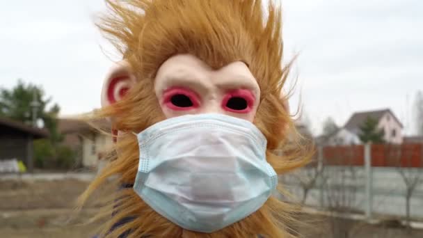 Обезьяна в медицинской маске на улице выглядит испуганной и расстроенной — стоковое видео