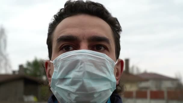 Итальянский мужчина в медицинской маске на улице выглядит испуганным и расстроенным — стоковое видео