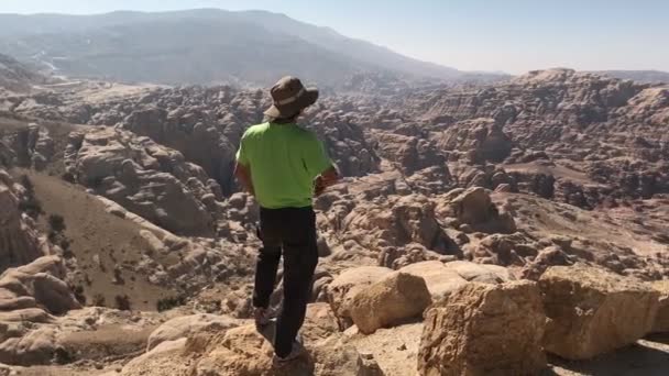 Homem de pé à beira das montanhas levantar as mãos olhando para a bela paisagem do deserto — Vídeo de Stock