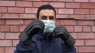 Maskeli adam boks eldiveni giyiyor, çıldırıyor, kendini görünmez tehditten korumaya çalışıyor.