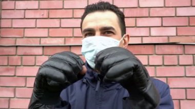 Maskeli adam boks eldiveni giyiyor, çıldırıyor, kendini görünmez tehditten korumaya çalışıyor.