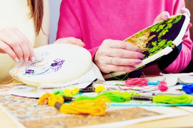 Kadınlar birlikte nakış işliyor. İplikleri, resimleri, iğneleri olan bir iş yeri..