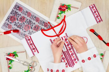 Geleneksel Ukrayna tişörtlü kız / kadın elleri çocuklar için nakış işleme kırmızı gömlek. Arkaplanda nakış şeması, makas ve renkli iplikler.