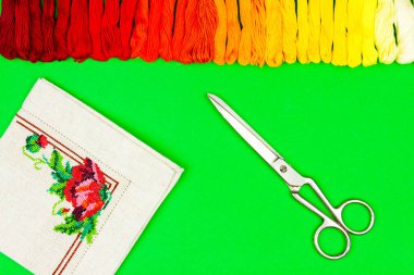 Dikiş ögelerinin renkli yeşil arkaplanı: nakış çerçevesi, palet renkli iplikler ve nakış deseni. Nakış ve dikiş konsepti