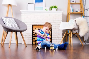 Kozmosun oyuncak üreticisi ile oynayan genç erkek çocuk: roket, mekik, gezgin, uydu ve astronot oyuncak evde rahat iç mekanda ahşap zemin üzerinde