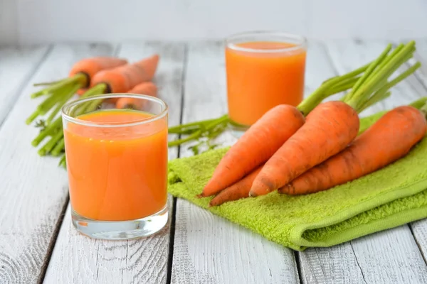 Δύο ποτήρια φρέσκο χυμό καρότου και φωτεινά πορτοκαλιά καρότα δέσμη — Φωτογραφία Αρχείου