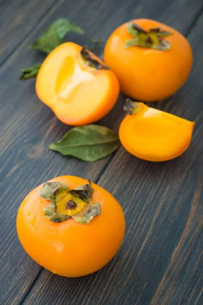 Sliced ripe persimmons with green leaves — Stock Photo, Image