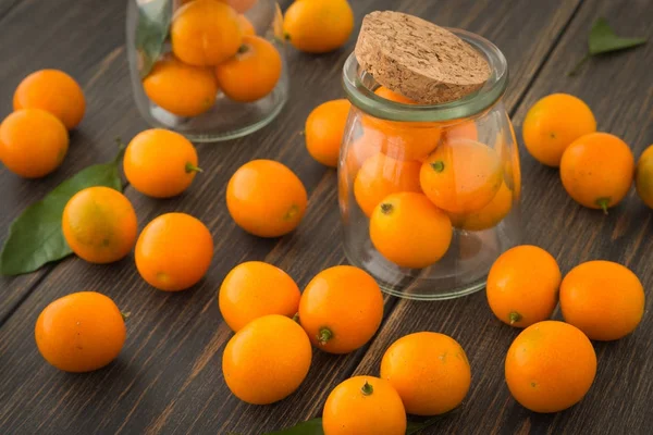 Cominhos de laranja frescos ou kumquats com folhas verdes em latas de vidro — Fotografia de Stock