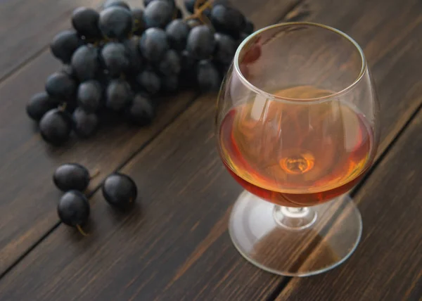 Un snifter de vidrio de brandy o coñac con un montón de uvas negras — Foto de Stock