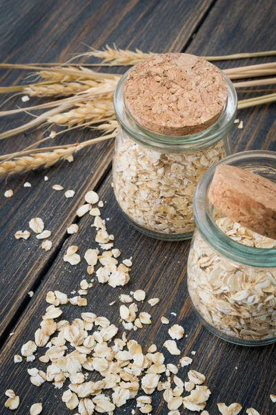 Dry rolled oats or oat flakes in craft glass jars with oat spike
