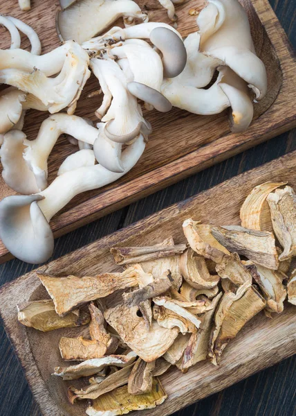 Cogumelos frescos e secos em placas de madeira artesanal — Fotografia de Stock