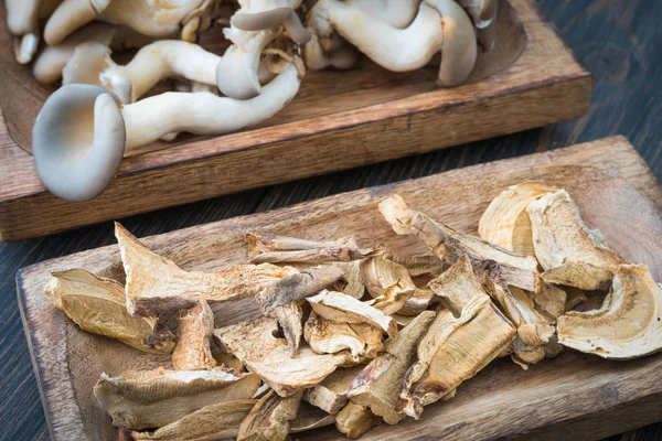 Cogumelos crus e secos em placas de madeira artesanal — Fotografia de Stock