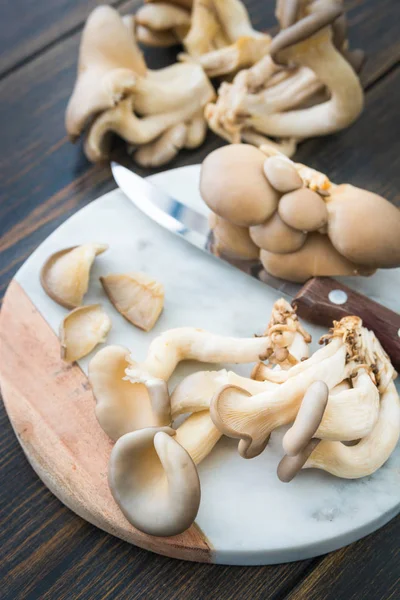 Cogumelos de ostra crus cortando na placa de corte de mármore — Fotografia de Stock