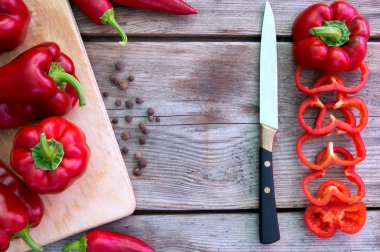Taze sebze kırmızı tatlı biber ve sıcak biber, eski ahşap arka plan üzerinde bıçak ile