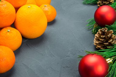 Portakal ve mandalina şube Noel ağacı, kırmızı top ve koni siyah beton zemin üzerine