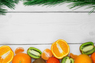 Beyaz ahşap rustik arka planda meyve portakal, mandalina ve kivi şube Noel ağacı