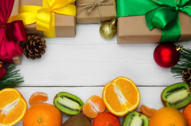 Beyaz ahşap retro arka planda şerit yay ve kırmızı topu ile meyve portakal, mandalina ve kivi ve hediye kutusu