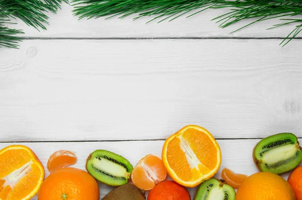 Beyaz ahşap rustik arka planda meyve portakal, mandalina ve kivi şube Noel ağacı