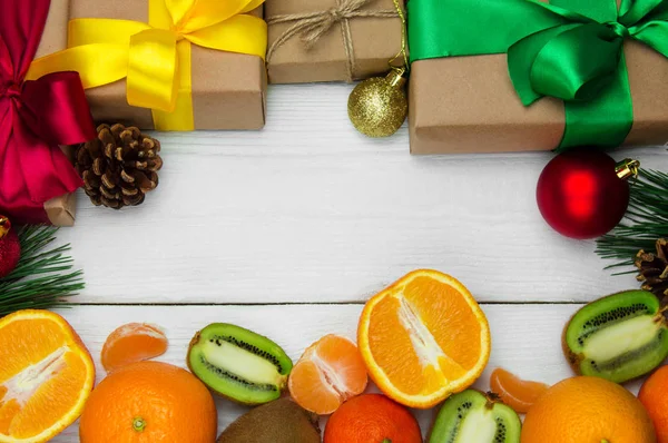 Beyaz ahşap retro arka planda şerit yay ve kırmızı topu ile meyve portakal, mandalina ve kivi ve hediye kutusu