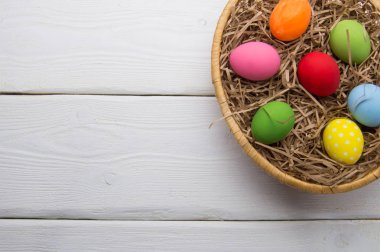 Beyaz ahşap arka plan en iyi beyaz üzerinde yuva beasket üzerinde renkli Paskalya yortusu yumurta