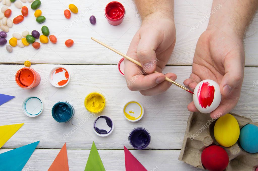 Painting easter eggs on wooden table with holiday decoration top view