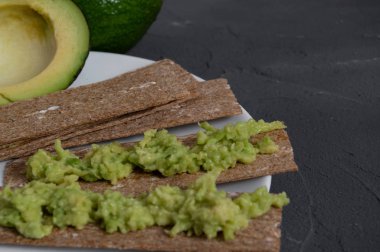 Tabağında parçalanmış avokado olan gevrekler.