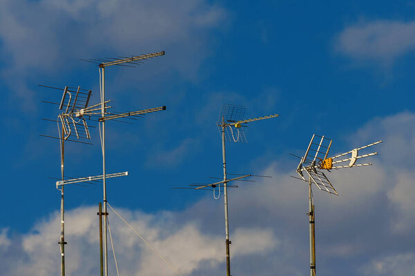 Различные виды телевизионных антенн и массивов с голубым небом и облаками
